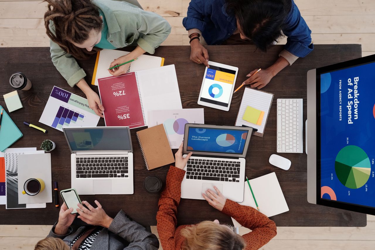 Une équipe diverse travaillant ensemble sur des stratégies de marketing digital autour d’un bureau, avec des ordinateurs portables et des tablettes.